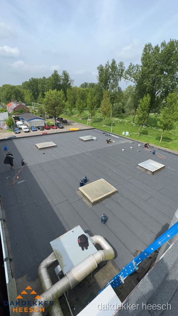 Dakdekker aan het werk op groot plat dak met bitumen in Heesch