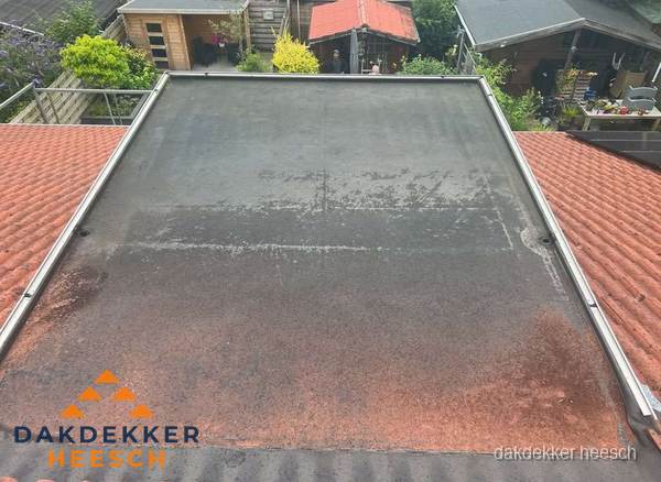 Verouderd plat dak met slijtage tussen schuine daken in Heesch Verouderd plat dak met slijtage tussen schuine daken in Heesch
