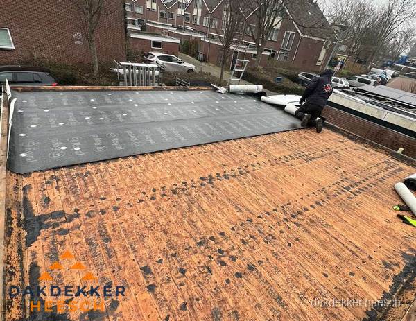 Dakdekker legt onderlaag op plat dak met houten constructie in Heesch