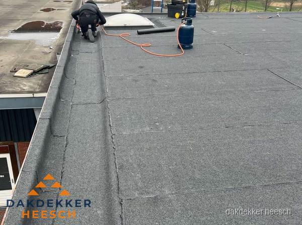 Dakdekker repareert bitumen dakbedekking op groot plat dak in Heesch